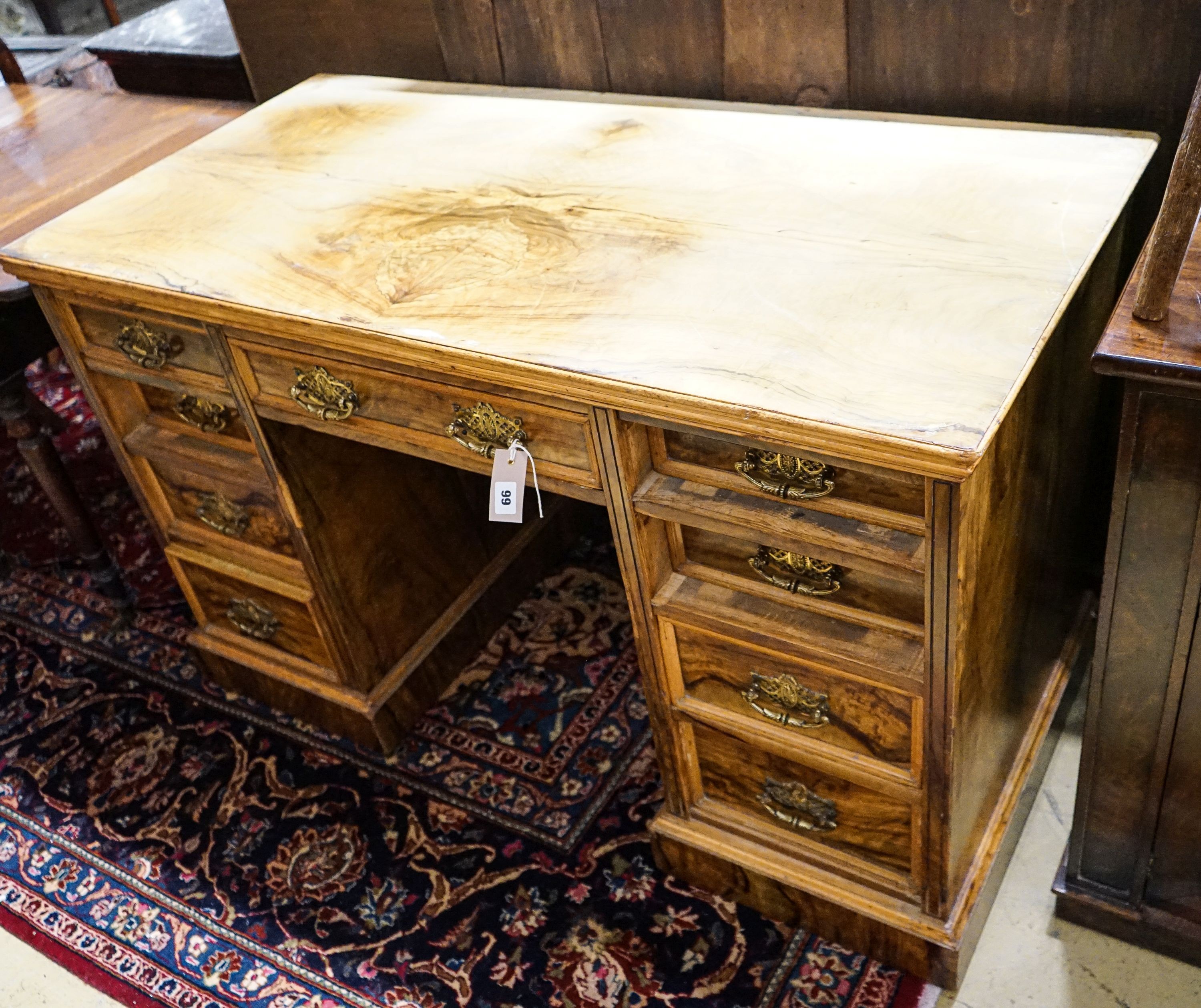 A late Victorian figured walnut twin pedestal desk, fitted with nine drawers with decorative gilt brass handles and plinth base, length 121cm, depth 60cm, height 75cm